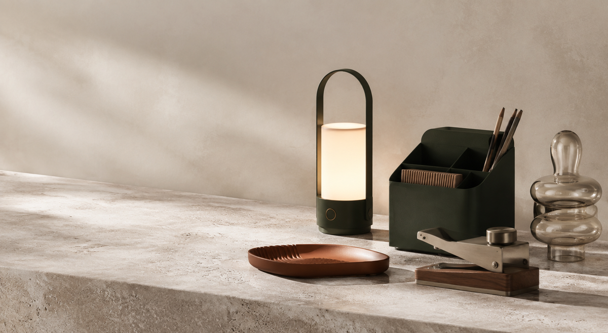 A curated arrangement of a portable lamp, desk organizer, and sculptural everyday objects.